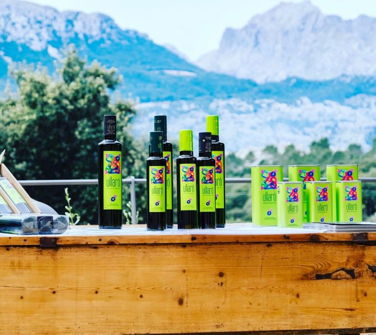 Imagen de varias botellas de aceite con la Serra de Tramunta na de fondo